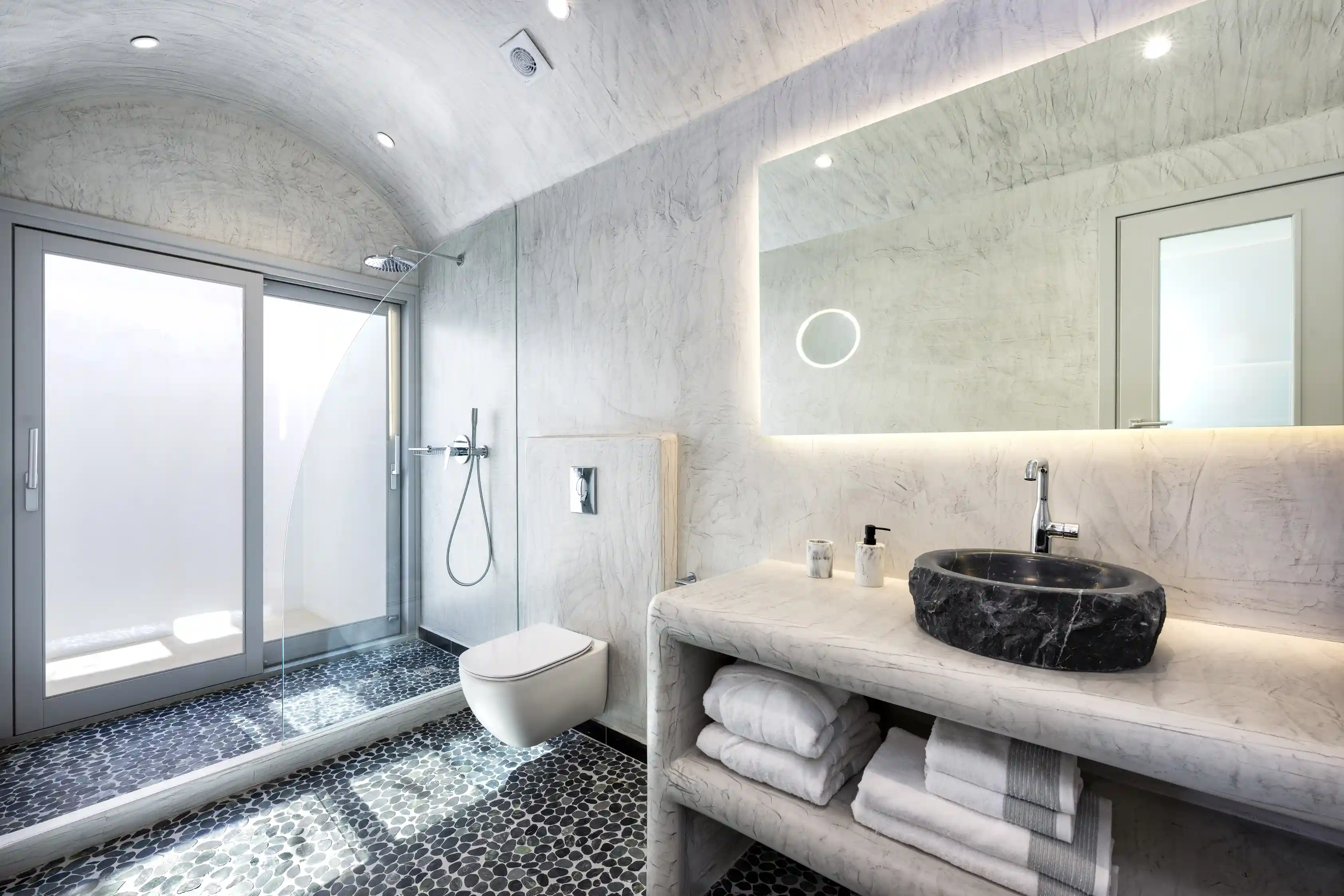 Superior Cave Villa bathroom with stone sink and pebble floor - Natural materials with luxury finishes